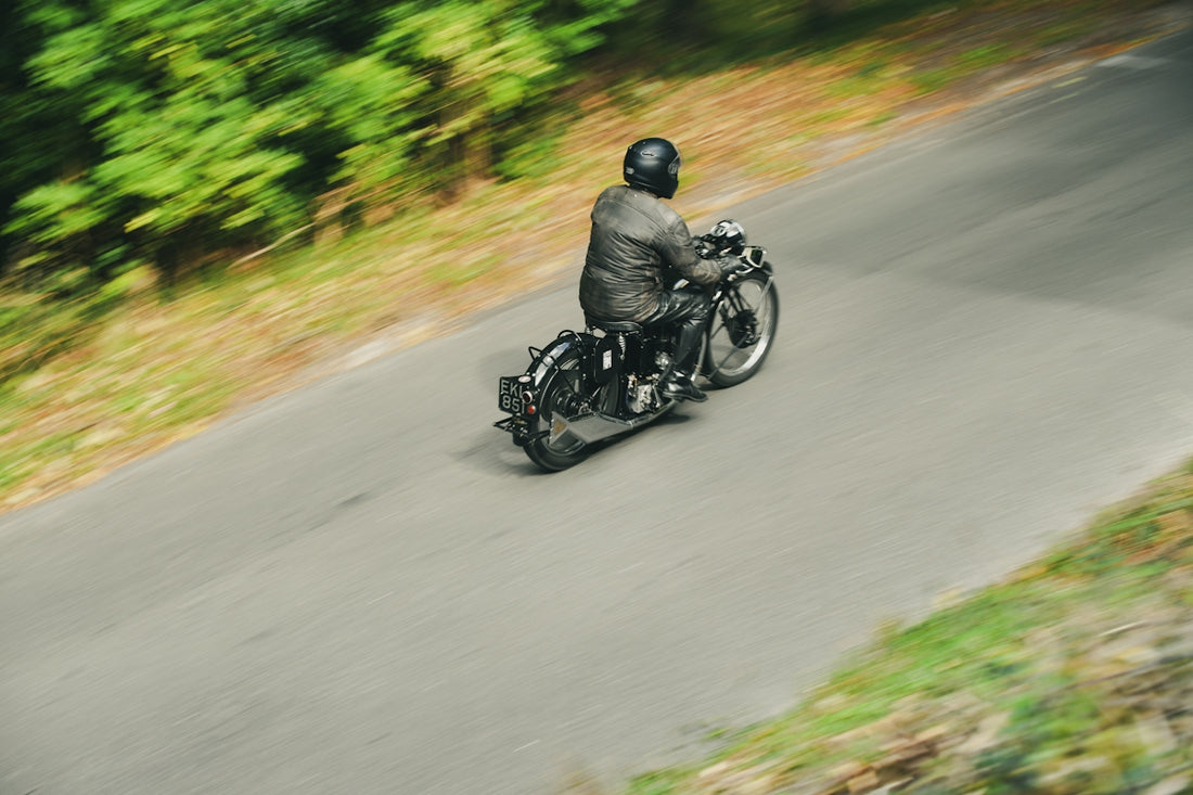 Man riding a vintage motorcycle on a winding road