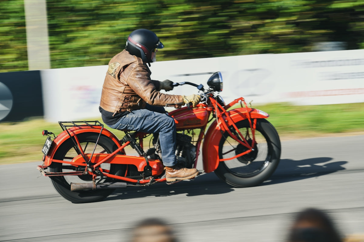 Man riding a vintage red motorcycle with motion blur