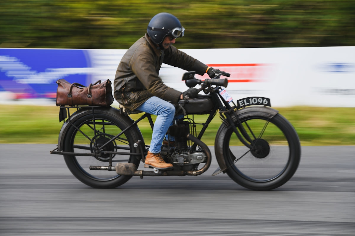 Man riding vintage motorcycle with leather bag on back
