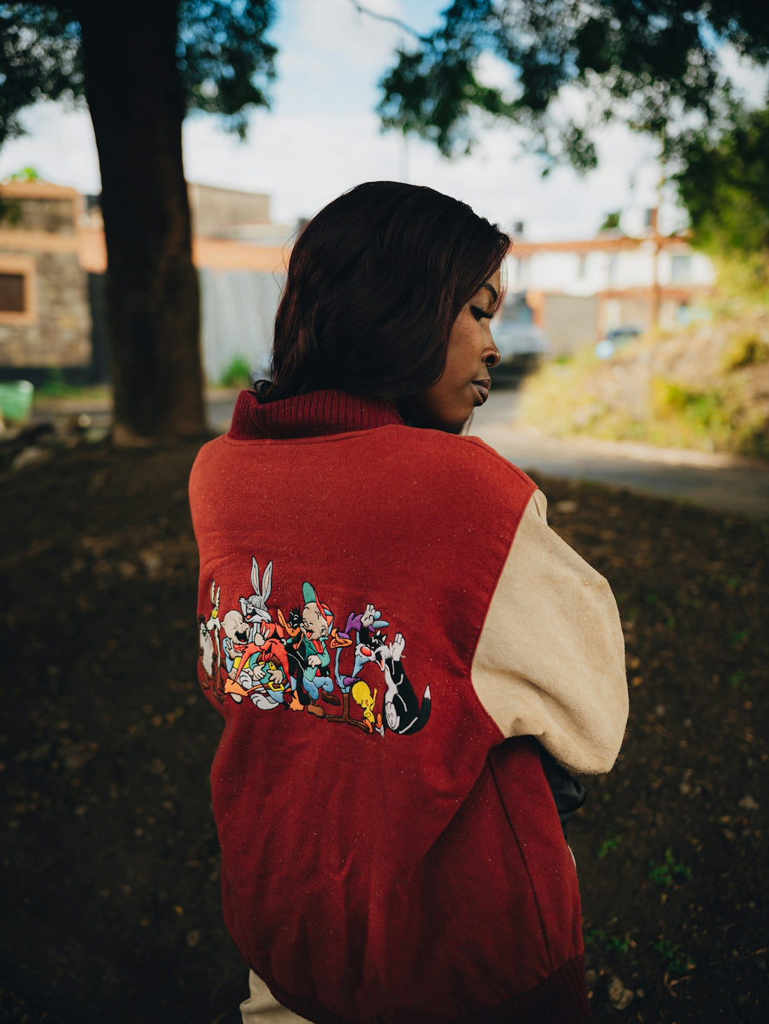 Woman wearing a red varsity jacket with looney tunes characters.